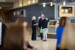 Three people talking in the background. Blurry heads in foreground.