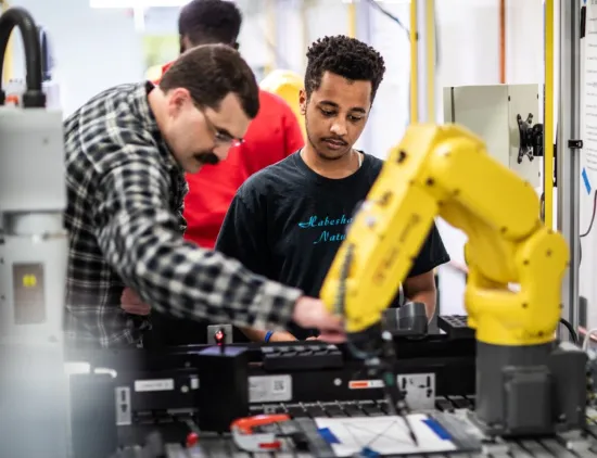  Yoni Abichu watching someone use a machine at the Academy Career Exploration Sessions.